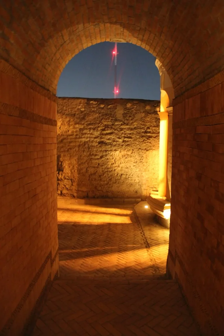 Pasaje abovedado de ladrillo que da al patio, iluminado de noche.